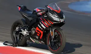 Czarny motocykl Aprilia 125 na torze wyścigowym. Zastanawiasz się, ile jedzie motor 125? Ten sportowy model jest gotowy do akcji.