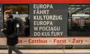 Ein Mann mit Rucksack steigt in einen Zug, der von Berlin nach Breslau fährt. Der Schriftzug "Europa fährt Kulturzug" ziert die Seite.