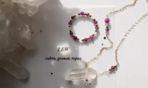 Jaki kamień dla Lwa? Rubin, granat i topaz w złotej biżuterii, obok kryształów.