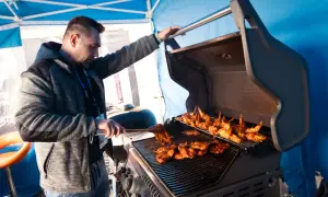 Mężczyzna przygotowuje pyszne skrzydełka i mięso na grillu. Idealne grillowanie w słoneczny dzień.