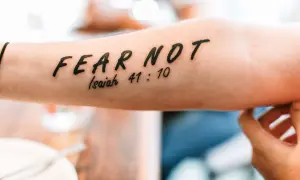 Tatuaż a religia: napis "FEAR NOT" z cytatem z Izajasza 41:10 na przedramieniu.