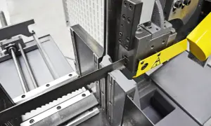 Precyzyjne cięcie drewna dzięki odpowiedniej prędkości piły taśmowej. Widoczna taśma tnąca i mechanizm prowadzący.