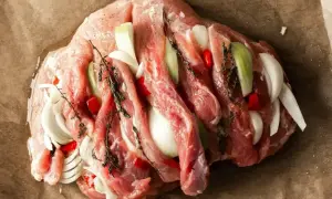 Surowa szynka z cebulą, papryczką chili i ziołami, gotowa na pyszny obiad.