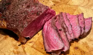 En saftig kalvstek, perfekt stekt till önskad kalvstek innertemperatur, skuren i skivor på en träskärbräda.