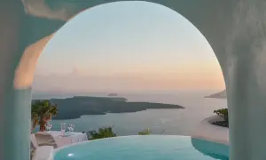 Romantyczne Santorini wakacje: basen z widokiem na kalderę, stół nakryty do kolacji przy zachodzie słońca. Idealne miejsce na niezapomniany pobyt.