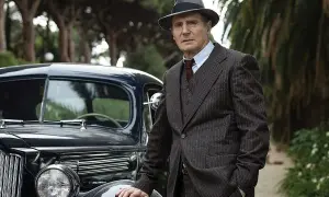 Philip Marlowe, detektyw z kryminałów Raymonda Chandlera, w eleganckim garniturze i kapeluszu, opiera się o luksusowy samochód z lat 40.