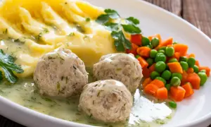 Kotlety mielone w sosie, puree ziemniaczane i warzywa na talerzu.