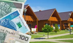 Polskie banknoty na tle drewnianych domków letniskowych.