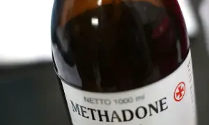 Butelka z ciemnobrązowego szkła z etykietą "Methadone" i symbolem krzyża.
