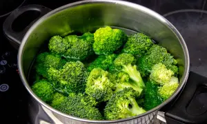 Brotes de brócoli frescos y verdes sumergidos en agua hirviendo en una olla de metal. Preparando para cocer brócoli.