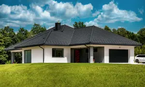 Nowoczesny dom z ciemnym dachem, którego grubość dachówki ceramicznej zapewnia trwałość. Otoczony zielenią, z podjazdem i białymi ścianami.