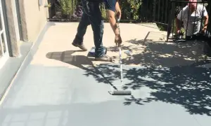 Peinture carrelage extérieur avant après : un homme peint une terrasse grise avec un rouleau, transformant l'espace.