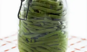Ein Glas mit sauren Bohnen, bereit zum Einlegen. Die grünen Bohnen sind dicht gepackt und schimmern im Glas.