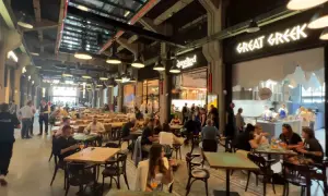 Tętniący życiem food hall w Gdańsku. Ludzie siedzą przy stołach, jedzą i rozmawiają. W tle widać lokal "Great Greek".