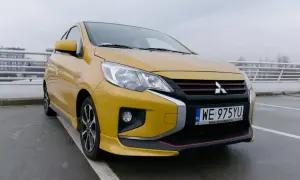 Żółty Mitsubishi Space Star 2004 z czarnym grillem i czerwonymi akcentami stoi na parkingu.