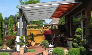 Moderne Terrassenbeschattung Ideen: Eine elegante Pergola mit ausfahrbarem Markisen-Dach schützt die gemütliche Sitzecke im Garten.