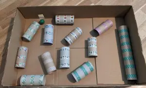 Karton basteln: Eine Murmelbahn aus Papprollen, verziert mit buntem Klebeband, wartet auf ihre erste Kugel.