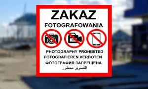 Znak ZAKAZ FOTOGRAFOWANIA z ikonami aparatu, kamery i telefonu komórkowego w czerwonych okręgach.