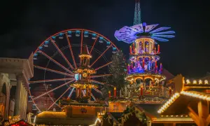Ein beleuchtetes Riesenrad in Karlsruhe strahlt neben einer Weihnachts-Pyramide.