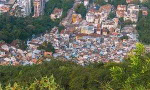 Widok z góry na gęsto zabudowaną fawelę w Brazylii, otoczoną zielenią. Czy Brazylia jest bezpieczna? To pytanie nurtuje wielu turystów.