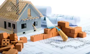 Modello di casa in costruzione su progetti, mattoni e cazzuola. Pianificazione per il rinforzo fondazioni esistenti.