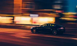 En mörk elbil susar fram i stadens ljus. Spännande fakta om elbilar kan du hitta här.