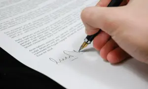 Firma su un documento, con una penna stilografica che scrive. Il peritale significato di un accordo si concretizza in questo gesto.