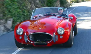 Ein Mann fährt einen roten Shelby Cobra 427 auf einer kurvigen Straße.