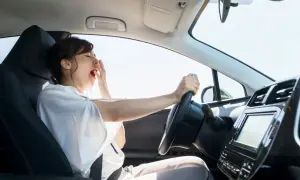 Mujer bostezando al volante. La fatiga puede alterar el tiempo de reacción del conductor, haciendo que el viaje sea peligroso.