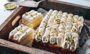 Ein köstlicher Joghurt Kuchen mit luftiger Creme und gehackten Pistazien, serviert auf einer rustikalen Holzschale.