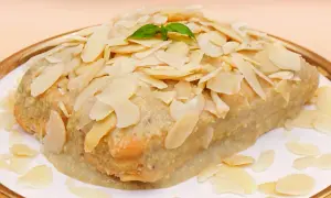 Szybkie ciasto z bananami i budyniem, polane kremowym sosem i posypane płatkami migdałów. Idealne na deser!