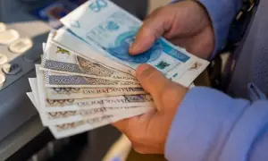 Ręce trzymające polskie banknoty, w tym 50 i 200 zł. Czy to kwota, która pomoże ustalić, ile wynosi renta alkoholowa?