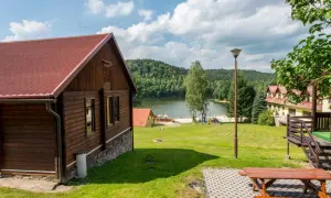 Drewniane domki nad jeziorem w Dolnośląskim, z placem zabaw i widokiem na las.