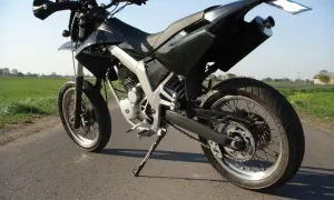 Czarny motocykl typu supermoto, gotowy do jazdy po wiejskich drogach. Senda czeka na przygodę.