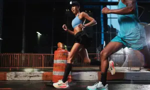 Coppia di runner notturni in città, impegnati in esercizi per migliorare la corsa. Le luci urbane illuminano la loro determinazione.
