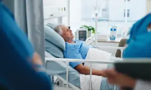 Starszy mężczyzna w szpitalnym łóżku, z kroplówką i monitorem, może mieć objawy hantawirusa.
