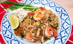En tallrik med pad thai med räkor, böngroddar, lime och gröna lökar. En klassisk thailändsk rätt.