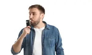 Mężczyzna w dżinsowej koszuli dmucha w alkomat. Czy można zbadać pracownika alkomatem? Tak, w określonych sytuacjach.