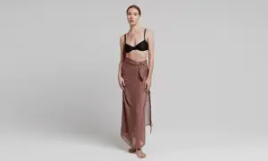 Modelka prezentuje, jak wiązać pareo w elegancki sposób. Długi, brązowy materiał owinięty wokół bioder, z ozdobnym węzłem.