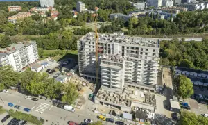 Budowa nowoczesnych, prywatnych mieszkań do wynajęcia nad morzem. Widok z lotu ptaka na osiedle w trakcie realizacji, z dźwigiem budowlanym i widokiem na morze w tle.
