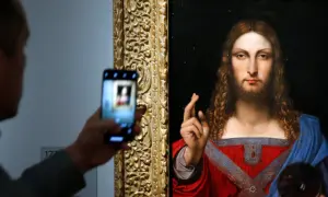 Osoba robi zdjęcie telefonem komórkowym obrazu "Salvator Mundi" przedstawiającego Jezusa.