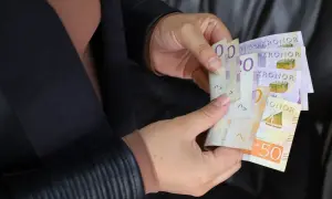 Ręce trzymają banknoty. Czy to sek, jaka to waluta? Widoczne są napisy "KRONOR" i cyfry 20, 50.