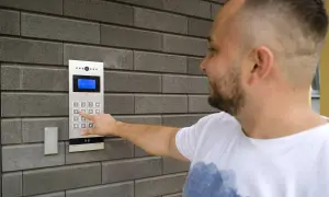 Mężczyzna naciska cyfrę na domofonie, pokazując, jak działa domofon w bloku.