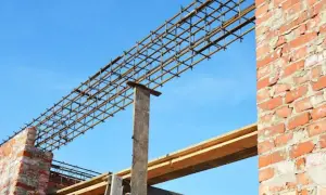Siatka zbrojeniowa nadproża 3m, gotowa do zalania betonem, na tle błękitnego nieba i ceglanej ściany.