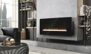 Nowoczesny, podłużny kominek elektryczny z realistycznym płomieniem, zamontowany na betonowej ścianie obok regału z książkami i roślinami.