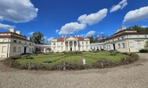 Pałac w stylu klasycystycznym z kolumnami, otoczony ogrodem z kwitnącymi tulipanami. Piękny ląd nad Wartą w słoneczny dzień.