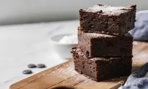 Pyszne, wilgotne brownie z kawałkami czekolady, posypane cukrem pudrem. Idealne na deser według prostego brownie przepisu.