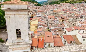 Vista dall'alto di San Marco in Lamis: un campanile in pietra domina un dedalo di tetti rossi e case arroccate tra le colline. Cosa vedere in questo borgo?