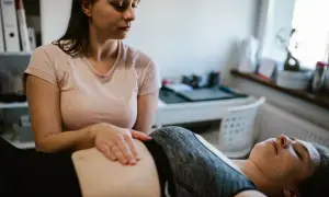 Fizjoterapeutka wykonuje masaż brzucha pacjentce leżącej na kozetce.