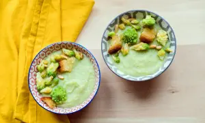 Zwei Schalen cremiger Gemüsesuppe, garniert mit Romanesco, Croutons und Pinienkernen. Ein köstliches Romanesco-Rezept für kalte Tage.